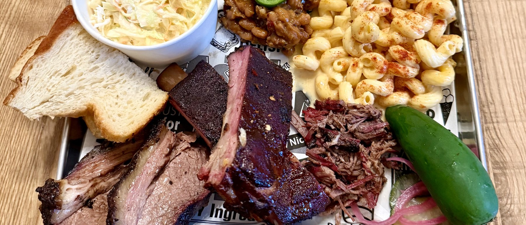 Que17 barbecue spread — brisket, ribs, pulled pork, mac and cheese, beans, slaw, and house pickles